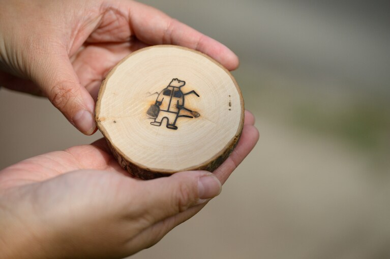 好きな形の木を選び、知床のシンボルキャラクター「知床トコさん」の焼き印を押して完成。ザ・ノース・フェイスを象徴する「マウンテンジャケット」を羽織っている姿がとてもオツ。