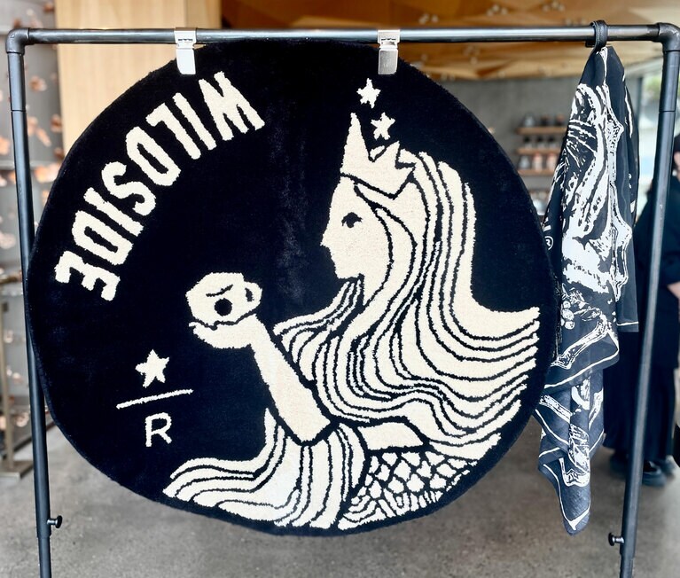 左の「WILDSIDE スターバックス リザーブ ラグ」（57,200円）は、ハンドメイドファクトリー「三好敷物」のオリジナルブランド「MIYOSHI RUG」によって一点一点手作業で仕上げられたもの。右は「WILDSIDE スターバックス リザーブ® スカーフ コーヒーオリジン」（10,450円）。スマトラトラやコーヒーチェリーなどを組み合わせた印象的なデザインです。