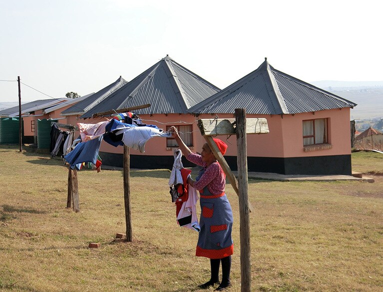 洗濯物を干すお母さん。カラフルな普段着はまるで衣装のように華やかで、それが村の風景によく映える。