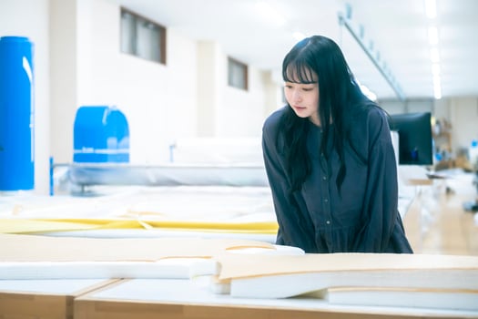 ネストローブ徳島工場を訪れた山田さん。服が仕立てられる過程に、山田さんも釘付け。リネン天然染めギャザーブラウス（C･GREY） 30,800円／ネストローブ