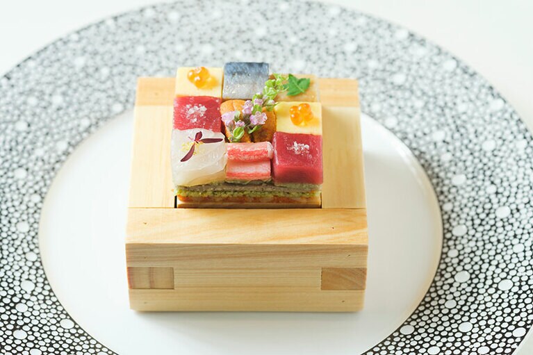 ウニ、タイ、カニなど高級な海鮮が乗った、前菜の箱寿司。4層のサラダには、アボカドやじゃがいも、クスクスなどが使用されています。