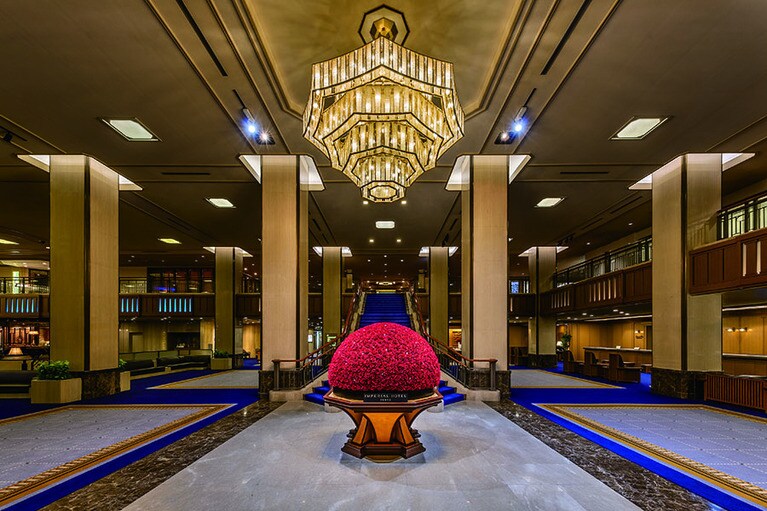 薔薇をイメージした金色のシャンデリアが季節の装花を華やかに照らす、帝国ホテル 東京の正面ロビー。