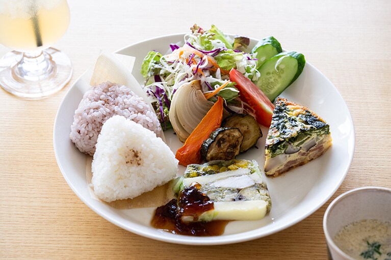 島のおむすびとともに佐渡産の野菜や魚介をテリーヌやフリッタータなどで味わえる「佐渡ジオパークプレート」1,300円。「西三川産りんご」400円。