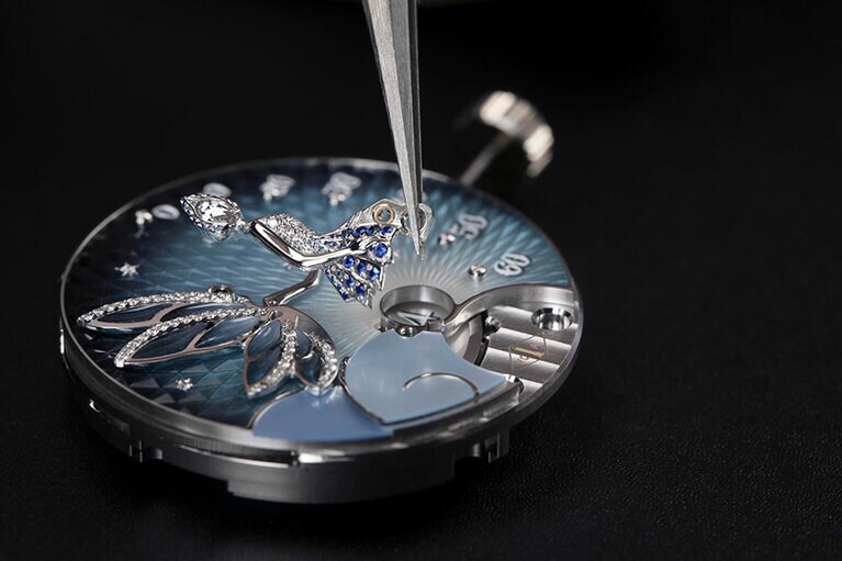 文字盤に妖精のモチーフをセットする様子。