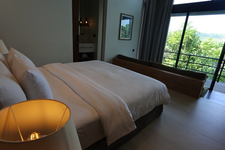 ベッドに横たわると、海や緑のビューが。ベッドフロアから一段下がったラウンジエリアには、ソファも。