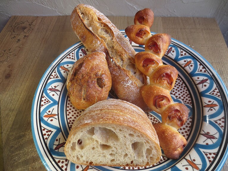 ハード系パン。左から時計回りに「日替わり素材　気まぐれカンパーニュ　イチジク」280円、「ホクシンのバゲット」350円、「ベーコンエピ」260円、「コンプレ」1/2 310円。