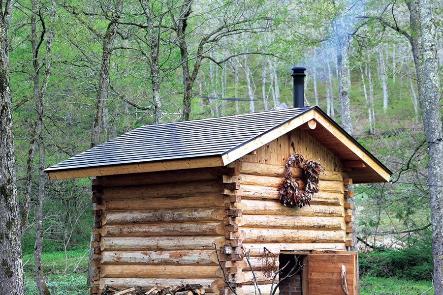森の中に佇む薪焚きのサウナ小屋(ゲストハウスLAMP野尻湖)。