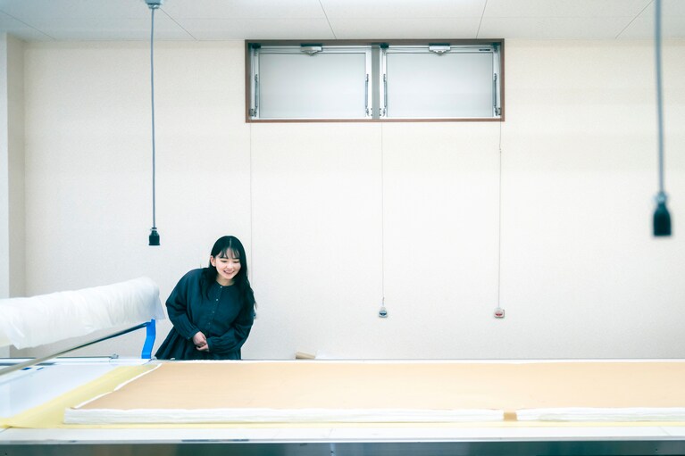 裁断には、徳島工場が2019年に新設した際に導入された、全長15mの延反機と自動裁断機（ＣＡＭ）を用いる。以前より多くの生地を一気に扱えるようになったにもかかわらず、1枚1枚の仕上がりの精度を維持するために、上限より量を減らして裁断しているそう。