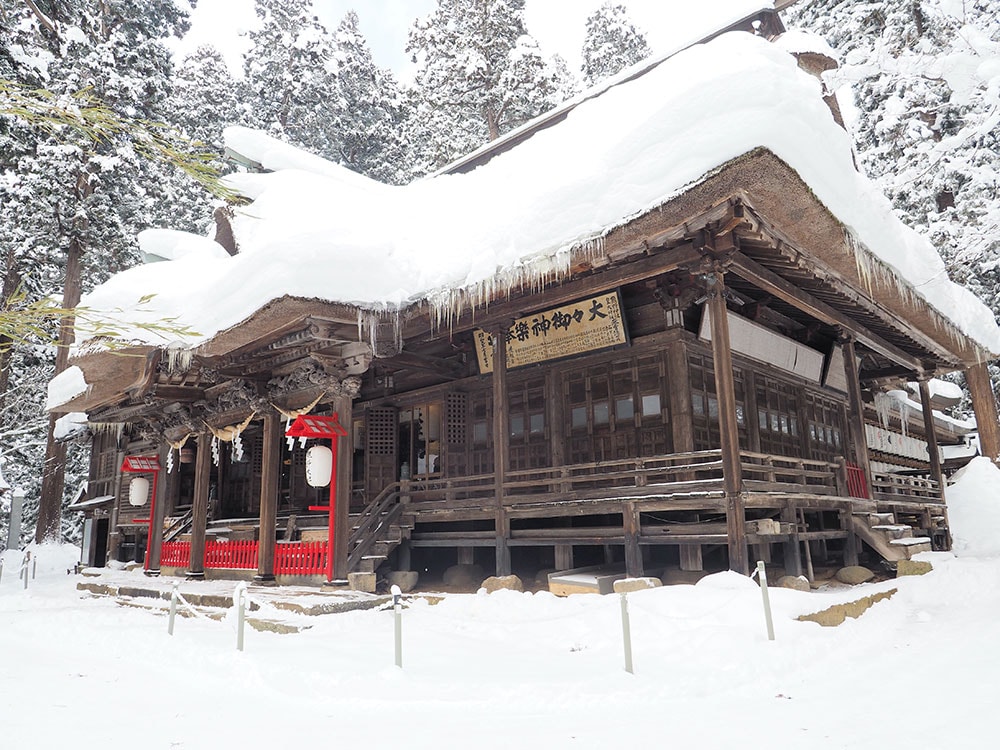 雪に覆われた茅葺き屋根の「熊野大社」の拝殿。神聖な空気の中で、美しい雪景色を楽しめる。