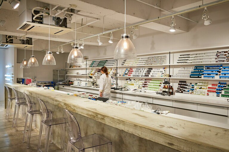 南青山・骨董通りにあるカラーズ本社のドアを開けると、いきなりラボが出現！　棚には精油や植物原料がズラリと並び、スポットに照らされたカウンターが。研究員も若くて(白衣を着ているけど)カフェのような雰囲気。