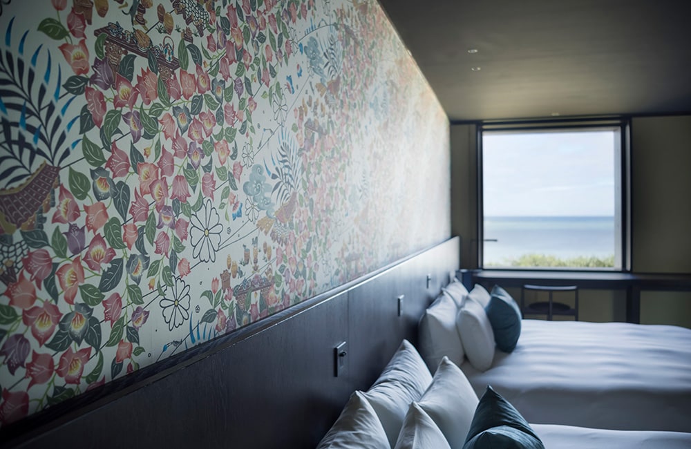 沖縄の言葉で星を意味する客室「フゥシ」。ブーゲンビリアをモチーフにした紅型の壁紙が空間を鮮やかに彩ります。