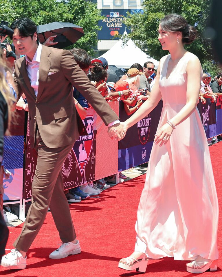 2024年7月、オールスター戦前のレッドカーペットで真美子さんの手を引く大谷選手。真美子さんは白いジャンプスーツに合わせ、パールのアクセサリーを着用　©時事通信社
