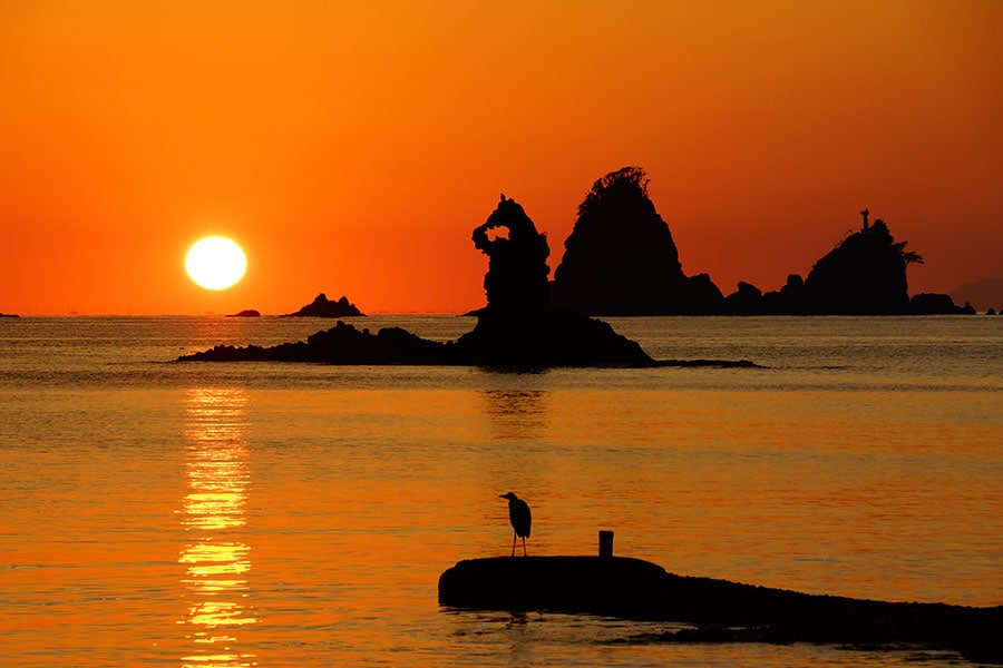「日本の夕陽百選」に選ばれた大田子海岸の夕陽。“メガネッチョ”と呼ばれる岩は、ゴジラに似ていることから“イズら”の愛称も。また、写真を横向きにすると、ムーミンのシルエットに……。©西伊豆町観光協会
