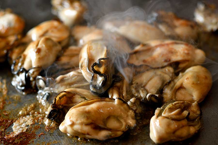 【鉄板・お好み焼き 電光石火】鉄板の上で旨そうなにおいを立ち上らせる広島産牡蠣。