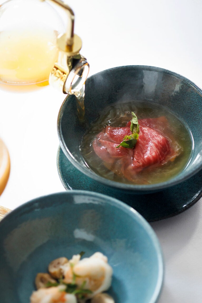 メイン料理の一つ、コラート地方産和牛のハーブコンソメスープ。サイフォンで煮立てたスープをレアの牛肉に注ぎ、その場で火を通すことで、ハーブの香りがいっそう引き立つ。