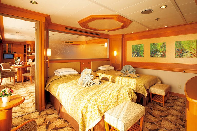 幅12mのワイドスパンベランダや大窓からの眺望が楽しめる円形ブロー＆ジェットバスを備える“グランドスイート”。ベッドルームでは伝統の花毛布がお出迎え。