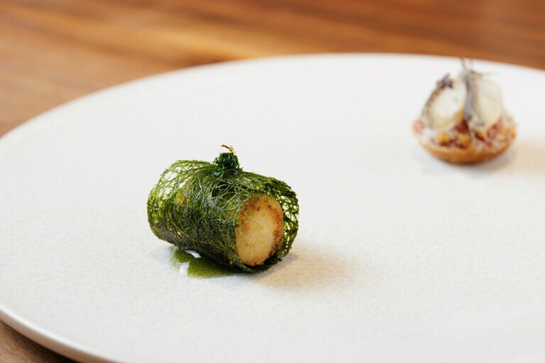 奥は山海のご馳走をあえて重ねた、韓牛とうなぎのタルト。コチュジャンと梅の風味が広がる。手前は太刀魚のコロッケを繊細なカムテ(甘海苔)で包み、二重衣のように。