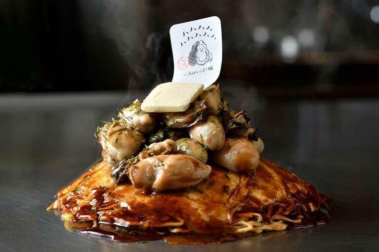 【鉄板・お好み焼き 電光石火】お好み焼きの上に築かれた牡蠣ピラミッドが圧巻、「マシマシ牡蠣」2,547円。