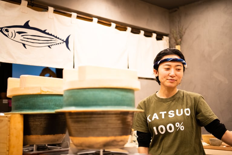 ねじり鉢巻きに、かつお愛あふれるオリジナルTシャツで店に立つ。