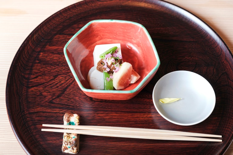 食前酒は菊花を浮かべた地酒。先附は胡麻豆腐と帆立、無花果、スナップエンドウ、赤田楽味噌で、器は当代（四代目）須田菁華作。