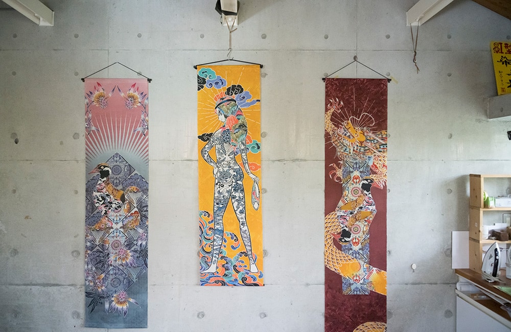 タペストリー3種。左から：ヤンバルクイナをモチーフにリアルな沖縄カルチャーを描いた〈ハイブリッドオキナワ〉、手塚プロダクション監修のもとに制作された〈TATOO GIRL〉、龍をモチーフに悟りの世界を独自の感性で描いた〈上求菩提〉。  