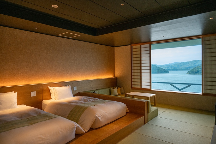 障子を開ければ穏やかな浜名湖の絶景が広がる客室。ベッドスローやクッションには、浜松の伝統的な織物、遠州綿紬が使われている。