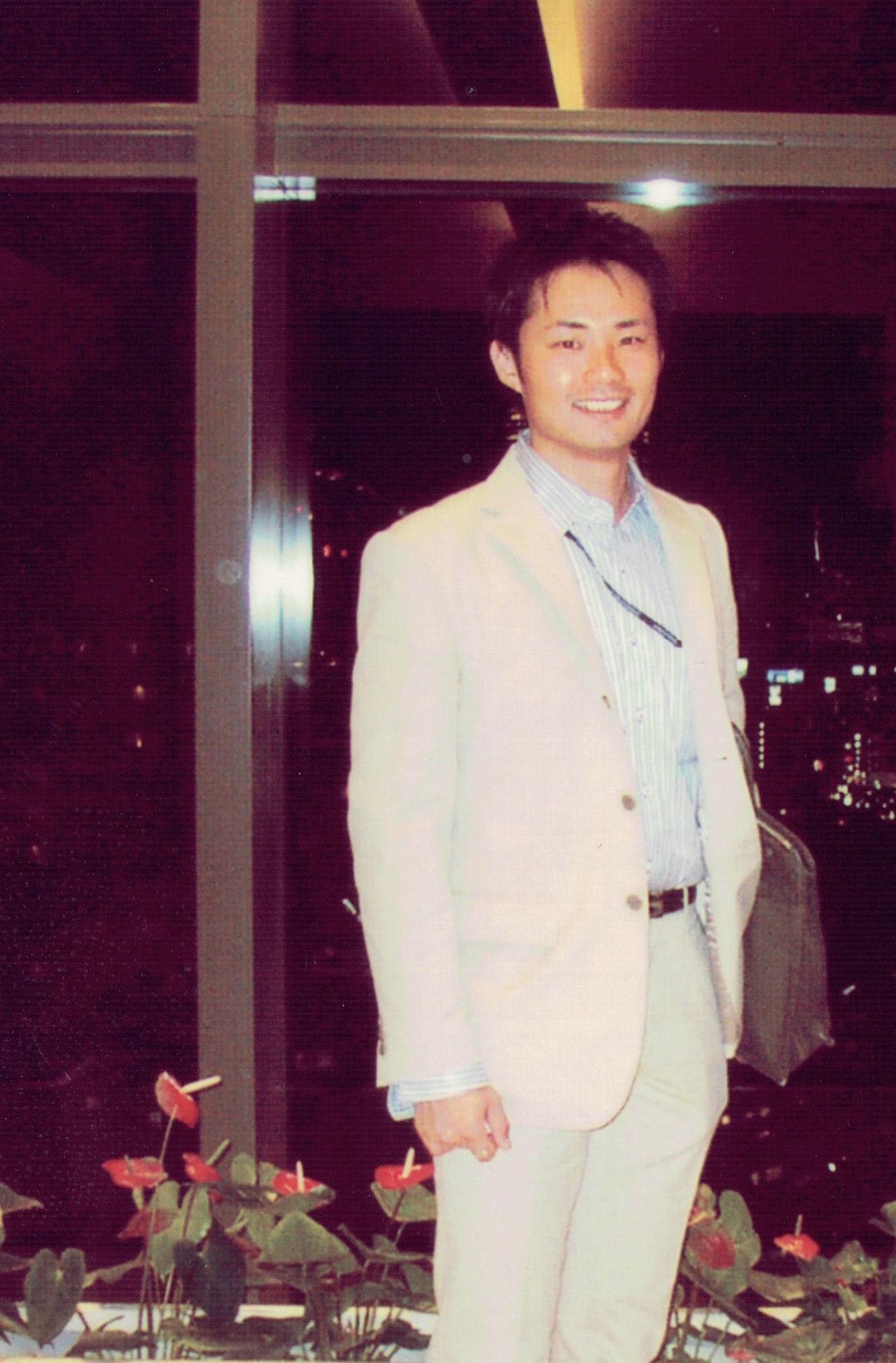 証券マン時代の杉村さん。上下白のスーツを着こなし、東京の夜景を見下ろす。（ご本人提供）