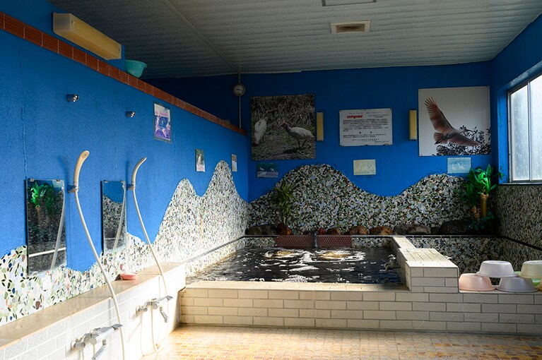 波をモチーフにしたようなレトロなタイルと青空のような壁が印象的な浴室。カランからも茶褐色の源泉が出ます。