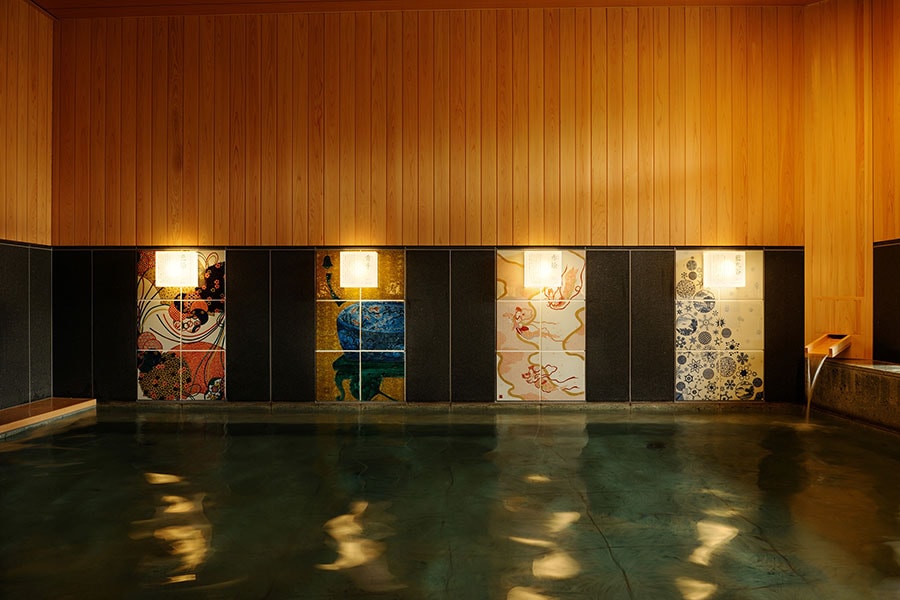 内風呂の壁面を彩る九谷焼のアートパネルを眺めながらのんびり湯浴み。