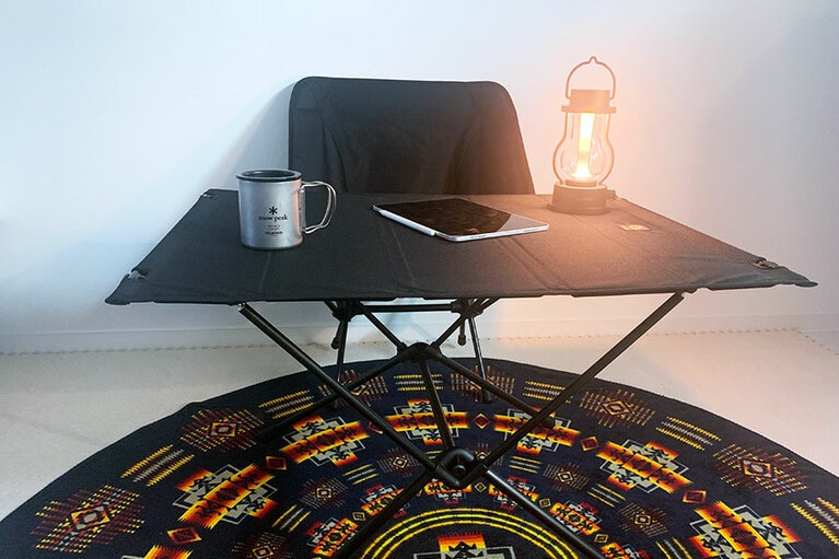 アウトドアグッズで固めた在宅環境。もともと持っていたスノーピークのマグで更にテンションアップ！　Helinox タクティカルチェア／ブラック 12,800円、Helinox タクティカルテーブルL／ブラック 18,500円、PENDLETON プリンテッド ラウンドタオル 7,800円(セール価格)、BALMUDA The Lantern Black 13,800円。※購入時の価格(すべて税抜)