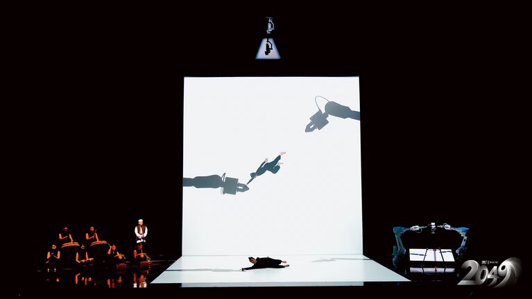 スクリーンに映し出されるのは、ひとりのパフォーマーと2本のロボットアームの影。重なり合いながら、絶妙な舞を繰り広げる。