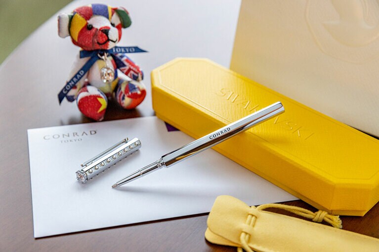 「コンラッドステイ with Swarovski」の特典。新作の「Swarovski」ボールペンと、“Swarovski® Crystals”のチャーム付きコンラッド・ベアは、1部屋につきそれぞれ1つプレゼントに。追加料金で購入も可能。