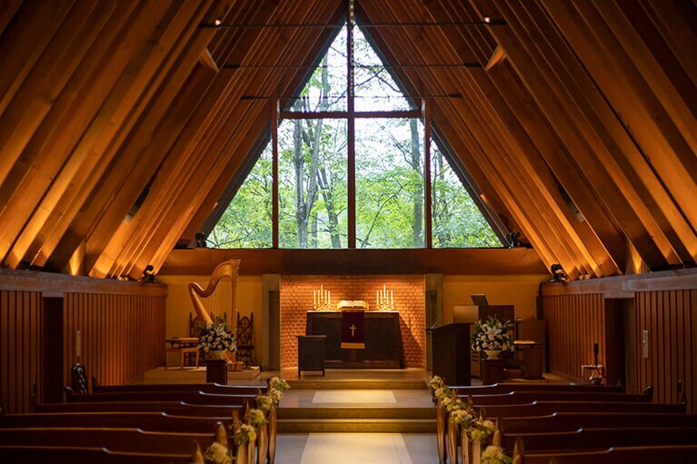 三角形の窓ガラスから見える四季折々の森の色がステンドグラスの代わりを果たす。