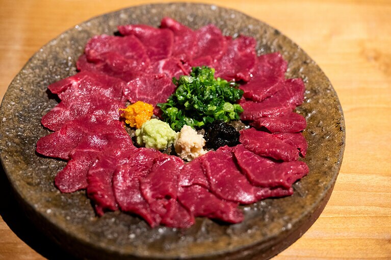 熊本名物の馬刺は外せない。小ネギ、海苔の佃煮、しょうが、わさび、柚子胡椒と薬味が豊富で味わいも豊か。昆布の旨みを感じられる、醤油ベースの自家製の詰めタレにつけて。