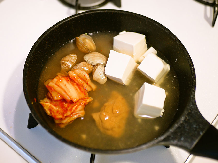 カップみそ汁の具、みそ、水、キムチ、ひと口大の豆腐を入れて中火にかける。