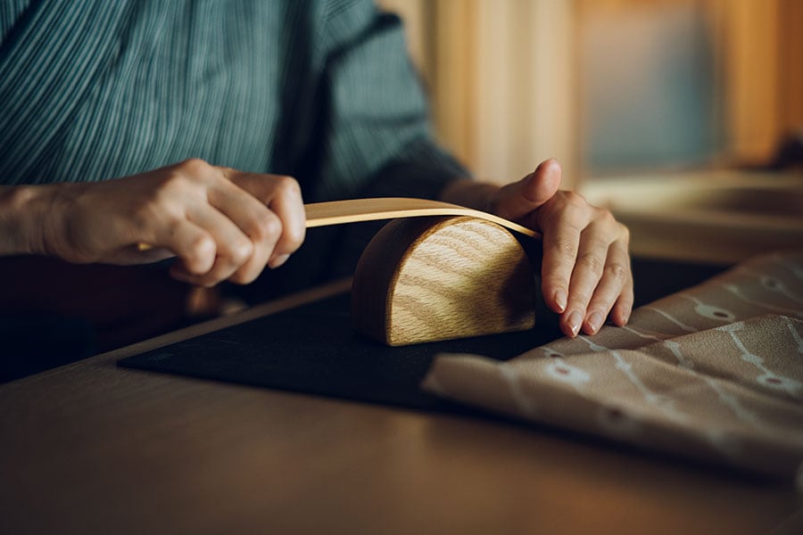 ヒノキの板をぎゅーっと曲げ、バッグのハンドルを作る。