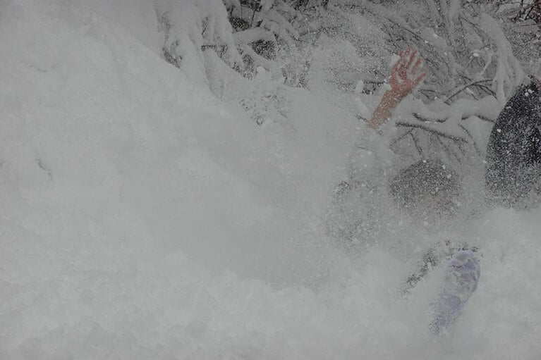雪煙を立てて転がる佐藤さん。