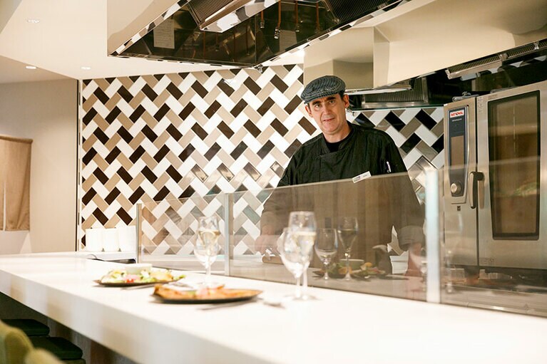 「シェフズカウンター」に立つマーク・ボナーさん。「大町市は水がとてもきれいな土地。自分で山菜を摘みにいったりもします」。