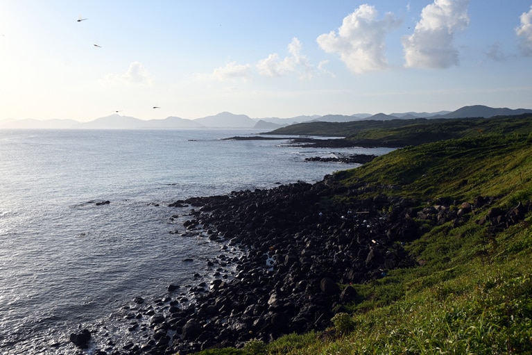 かつての溶岩なのか、黒い岩が転がる高崎ビーチの脇の浜。