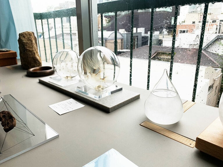 丸いガラスに植物の種子を閉じ込めたオブジェ L 18,000円、S 5,800円。手前右のストームグラスのオブジェ 3,800円。天候の変化によって中の結晶の表情が変わる。