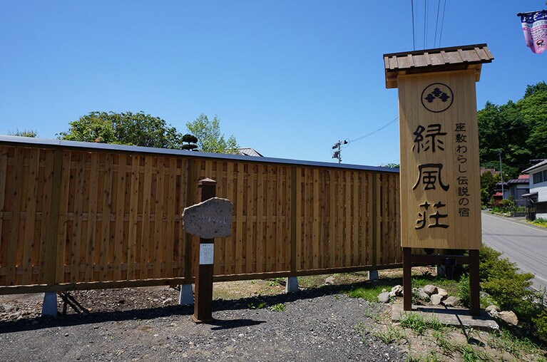 田畑が広がる風景のなかに建つ湯宿「緑風荘」。