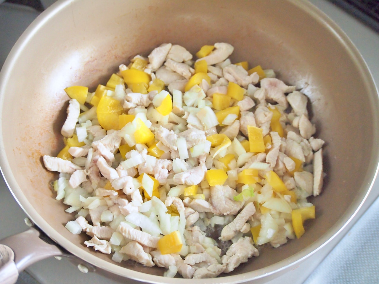 鶏肉の赤みがなくなってきたら、玉ねぎ、黄パプリカを入れてさらに炒める。