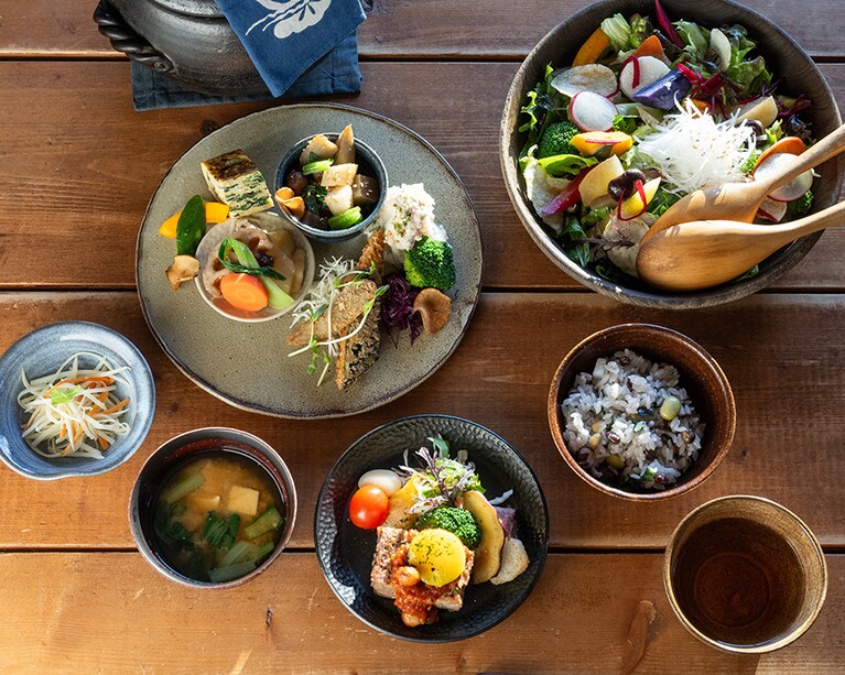 【かっこう料理店（更別村）】小さな森に隠れるようにたたずむ「かっこう料理店」は、北海道の大地が育む滋味をゆったりと味わえる人気店。食卓の主役は、自家農園の野菜や豆、近隣の生産者から届く季節の幸。店内には4組のテーブル席のみなので、予約はお早めに。