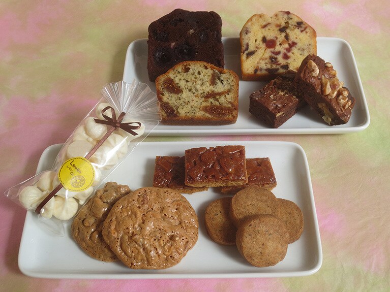 焼き菓子。奥の皿、左上から時計回りに「チェリーとチョコのパウンドケーキ」250円、「クランベリーとチョコチップのパウンドケーキ」250円、「PuPuPuの気まぐれ濃厚ブラウニー」1袋300円、「アールグレイといちじくのパウンドケーキ」250円。手前の皿、左から時計回りに「メレンゲ・レモン」1袋230円、「PuPuPuのフロランタン」1袋300円、「PuPuPuの香ばしクッキー」1袋300円、「PuPuPuのカリカリクロッカン」1袋260円。