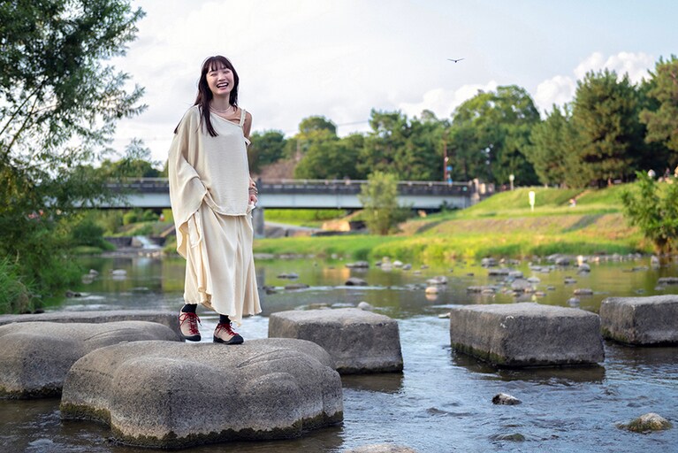 約70cm間隔で配置された飛び石も、難なくクリア。ロングスカートの裾から覗く「ジャスパー」は、フェミニンなスタイルのアクセントに。