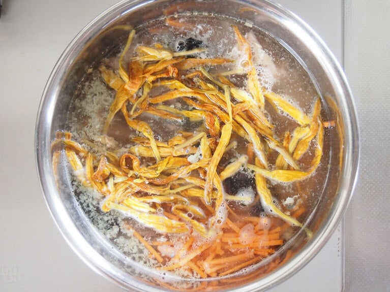 (2) 鍋に水、金針菜、黒木耳を入れて15分程置いて柔らかくなったら弱火で加熱します。鯖の水煮缶を汁ごと全て入れたら、(1)の人参、生姜を入れます。