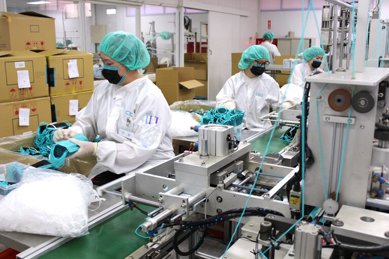 厳格な衛生管理下で粛々と生産されるマスク。作業員の方々もカラーサージカルを着けている点に注目