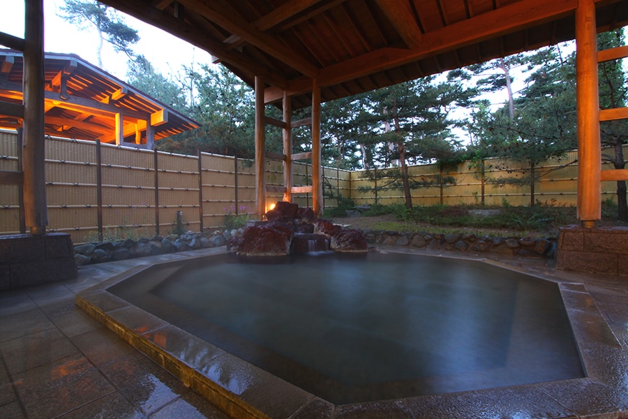 ライトアップされた松林庭園を望む露天風呂。冬は静かに雪見も。🄫八幡温泉 八幡館