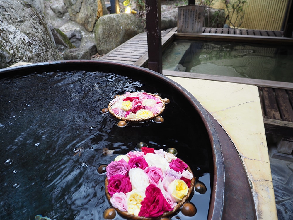「せせらぎの湯」女湯の露天風呂。釜風呂にバラが浮かべられている。