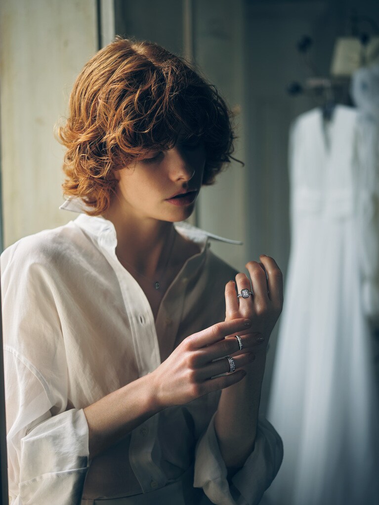 リング：〈左手・薬指〉「ヴァンドーム リズレ」ソリテール（WG×センターDIA1ct×ブラックラッカー）4,712,400円、〈右手・中指〉「キャトル ダブルホワイト」（WG×DIA×ホワイトセラミック）841,500円、〈薬指〉「キャトル ラディアント」（WG×DIA）2,917,200円　ペンダント「ヴァンドーム リズレ」（WG×DIA×ブラックラッカー）1,082,400円（すべて予定価格）／すべてブシュロン（ブシュロン クライアントサービス）　シャツ 311,300円（参考価格）／ブルネロ クチネリ（ブルネロ クチネリ ジャパン）　ラックにかけたドレス 319,000円（レンタル価格）／ケルビナ（ミラー ミラー 丸の内）